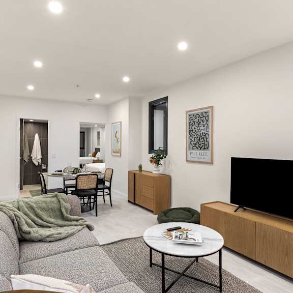 a modern living room with a grey sofa, a black tv, and a dining table with chairs.