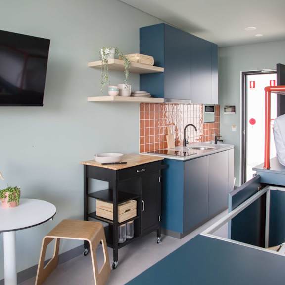 a small kitchen with a bed and a table in a small room