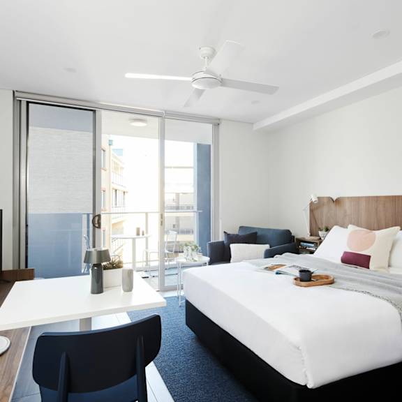 a bedroom with a bed and a desk and a balcony