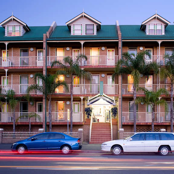 a building with palm trees and cars parked in front of it