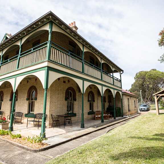 a large green and brick building with a porch and awning