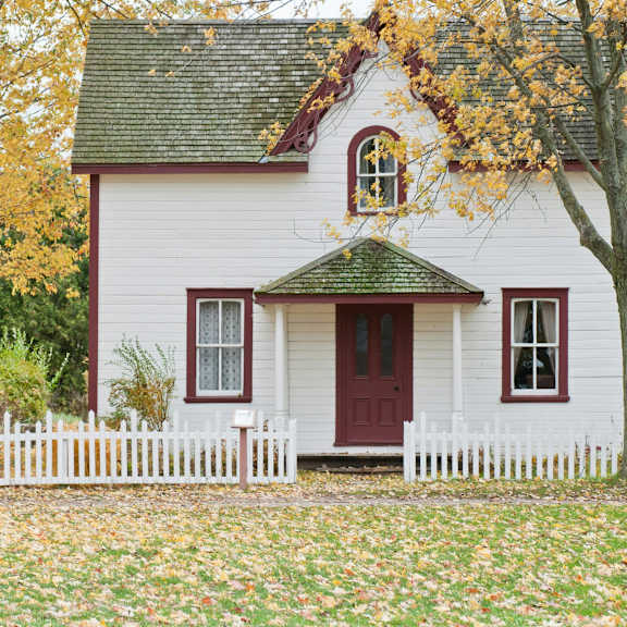 a white house with a red door and a green roof.