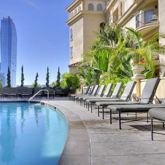 a pool area with lounge chairs and a tall building in the background.