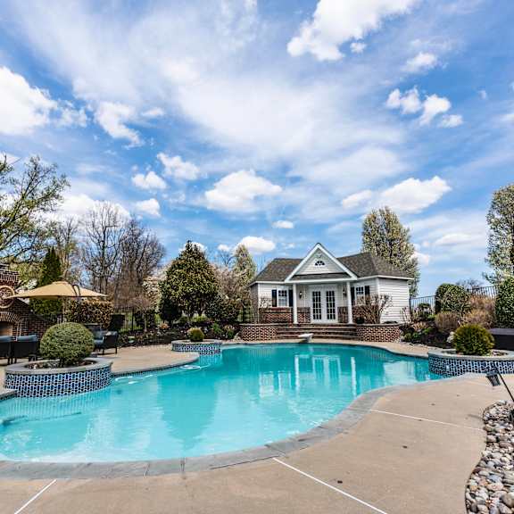 a large swimming pool in a backyard with a house in the background.