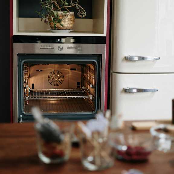 a modern kitchen with a white oven and a wooden table with glasses and bowls on it.
