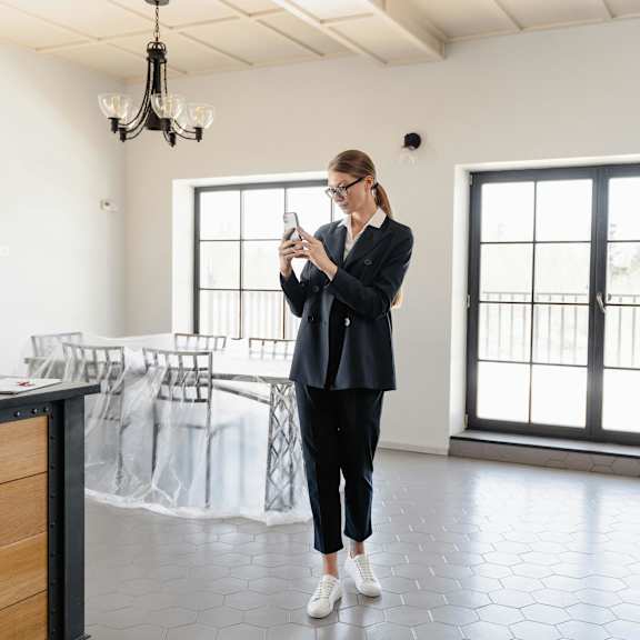 a woman in a black outfit is standing in a room with a wooden counter and a chandelier.