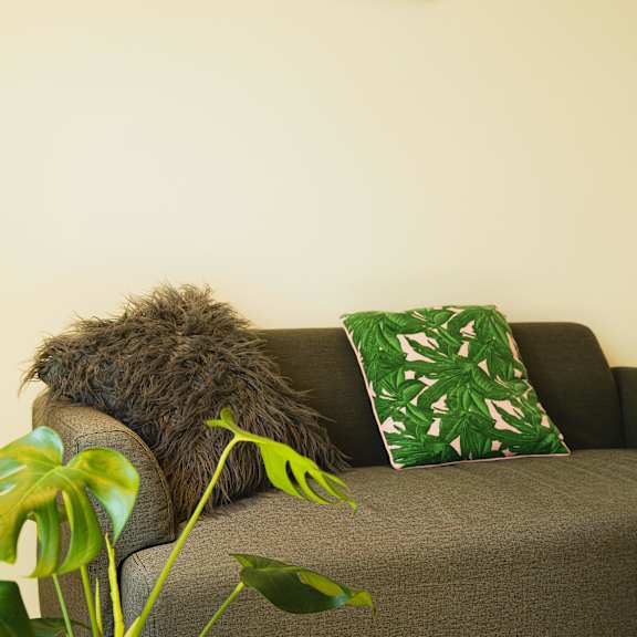 a couch with green pillows and a plant in a living room