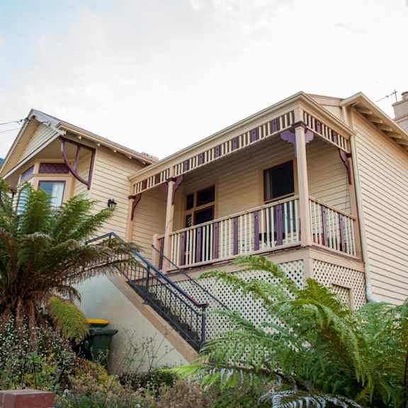 a yellow house with a balcony and a palm tree