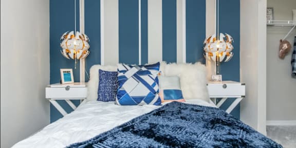 A bedroom with a white bed and blue and white striped walls.