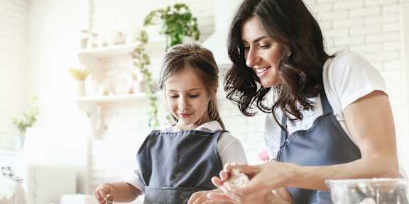 A woman and a child are making cookies together.