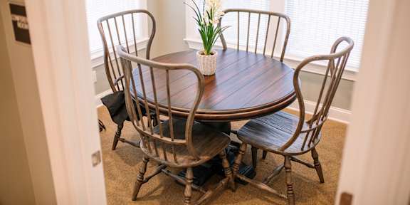 A table with chairs around it and a vase of flowers on the table.