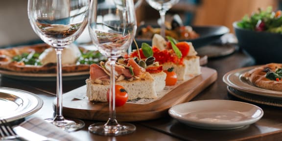 a wooden table topped with plates of sandwiches and wine glasses