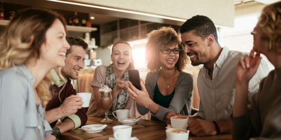 a group of people sitting around a table talking and laughing