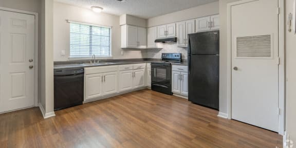 an empty kitchen with white cabinets and black appliances