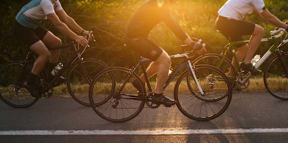 Three people riding bicycles on a road during sunset at Cru at Willows Apartments, Redmond