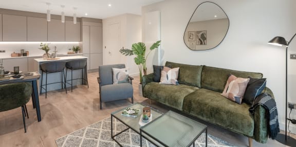 a living room with a green couch and a kitchen with a table and chairs