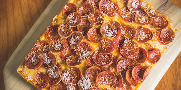 A pepperoni pizza on a wooden board.