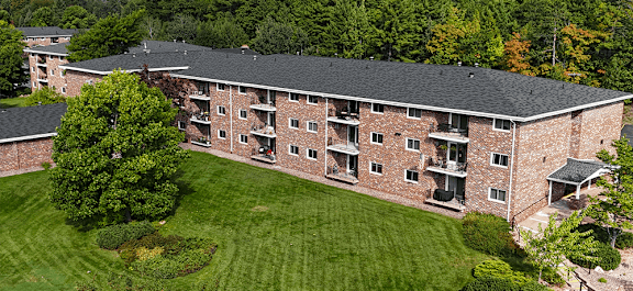 A large brick building with a green lawn in front.