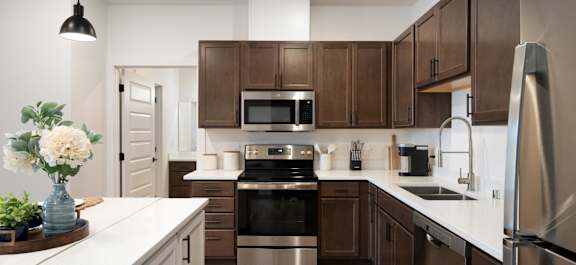 A modern kitchen with dark brown cabinets and stainless steel appliances.