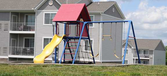 A red and yellow slide in front of a grey house.