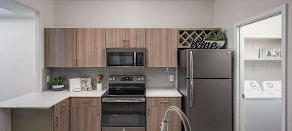 A modern kitchen with a stainless steel refrigerator and wooden cabinets.