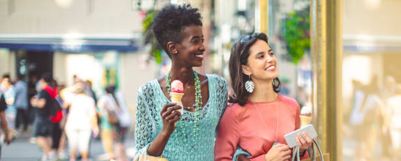 women walking down the street with shopping bags and ice cream