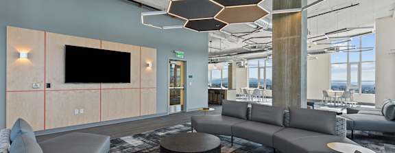 A modern living room with grey sofas and a wooden ceiling.
