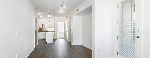 A long, empty hallway with white walls and wood flooring.