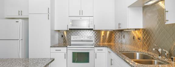 A kitchen with white cabinets and a granite countertop.