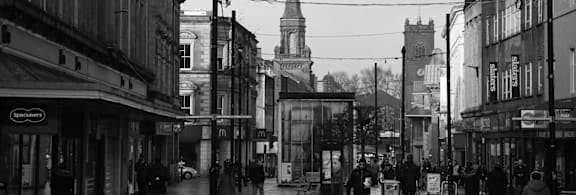 A black and white image of a row of houses with a street lamp in the foreground.