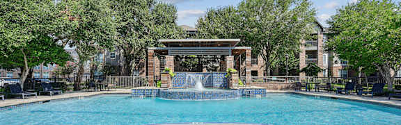 A large swimming pool with a waterfall and a pavilion.