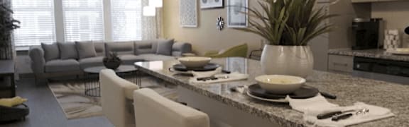 A modern kitchen with granite countertops and a dining area with a grey sofa.