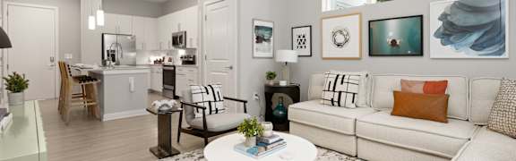 A modern living room with a white couch and a coffee table in the center.