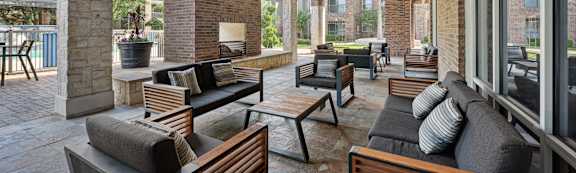 A patio with a couch, chairs, and a ceiling fan.