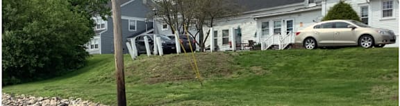 A house with a stone wall and a car parked in front.