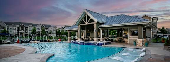 a large swimming pool with lounge chairs at night