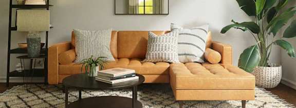A living room with a yellow couch, a black coffee table, and a large plant.