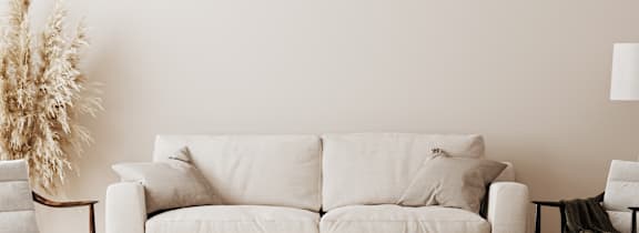 A white couch with a bowl on the floor in front of it.