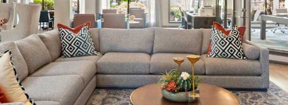 A grey couch with a red pillow is in the foreground of a well-decorated room.