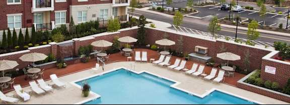 A large swimming pool surrounded by chairs and umbrellas.