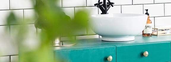 A white bowl is on a turquoise cabinet.