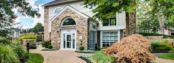 A house with a stone arched doorway and a brick pathway leading to it.
