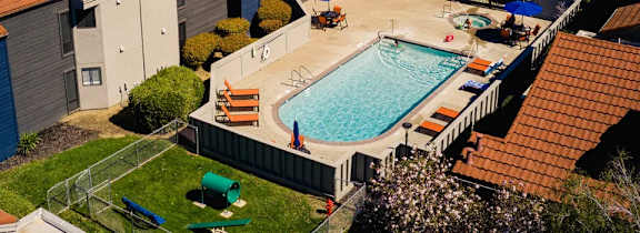 A small swimming pool surrounded by a fence and a few chairs.