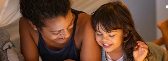 A couple is lying on a bed with pillows and a laptop.
