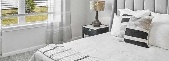 A bedroom with a large bed and two lamps.