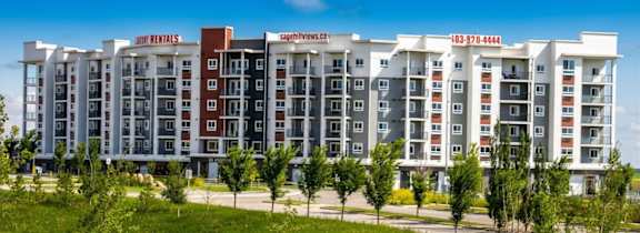 A large, modern apartment building with a red and white sign on the top.