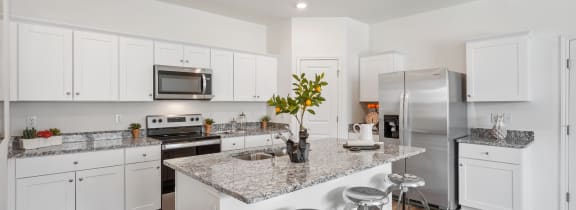 an open kitchen with white cabinets and a marble counter top