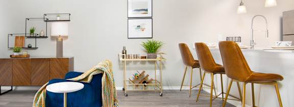 a living area with a blue chair and a kitchen with a bar table and chairs