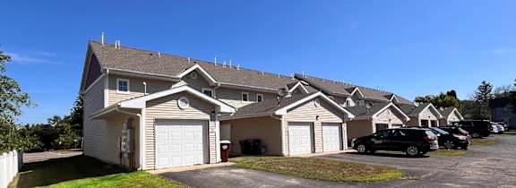 A row of houses with garages and cars parked in front.