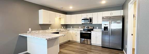 A kitchen with a marble countertop and stainless steel appliances.
